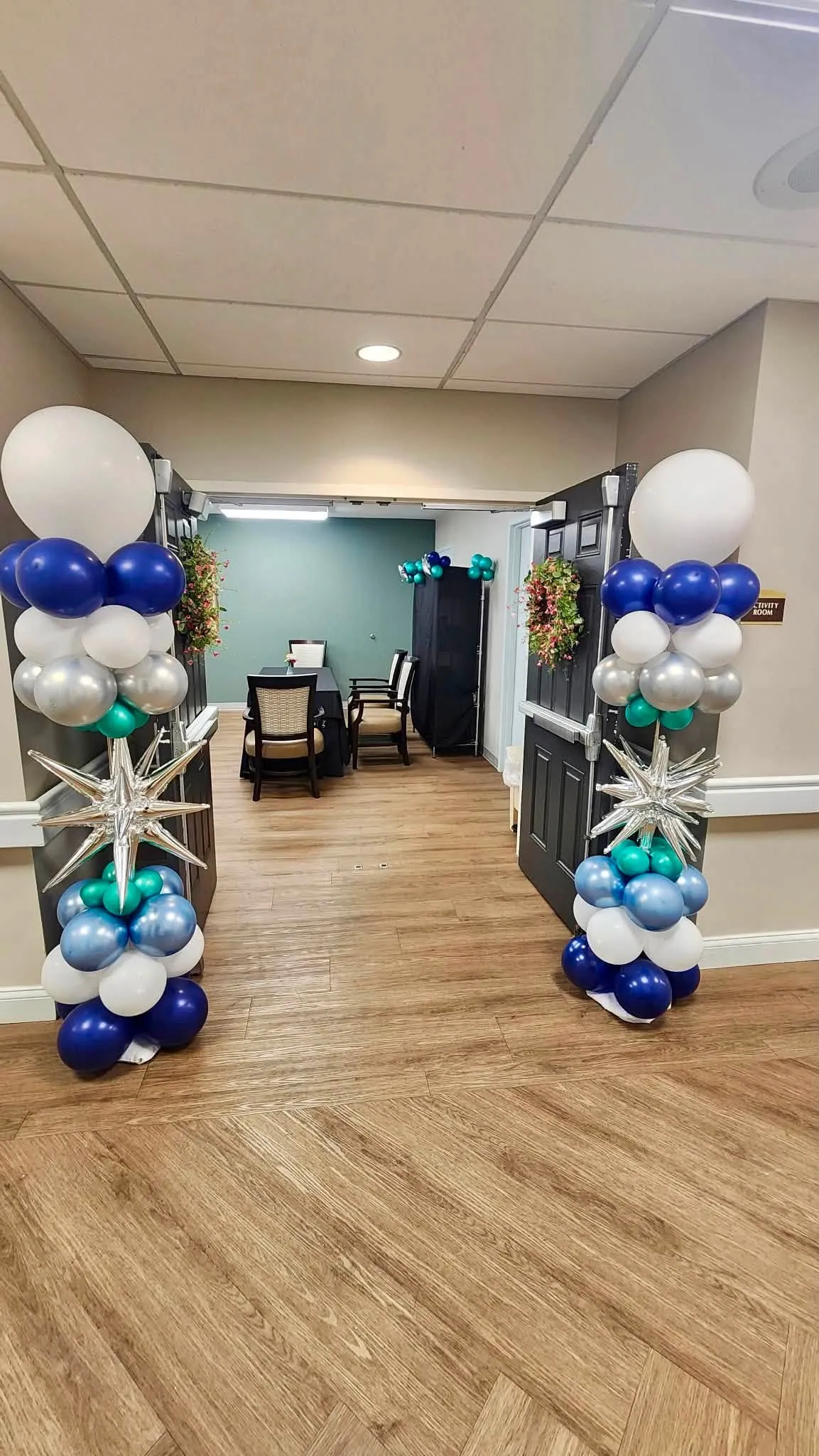 Two balloon columns of navy, white, silver, teal and chrome blue with silver starbursts on either side of an open doorway