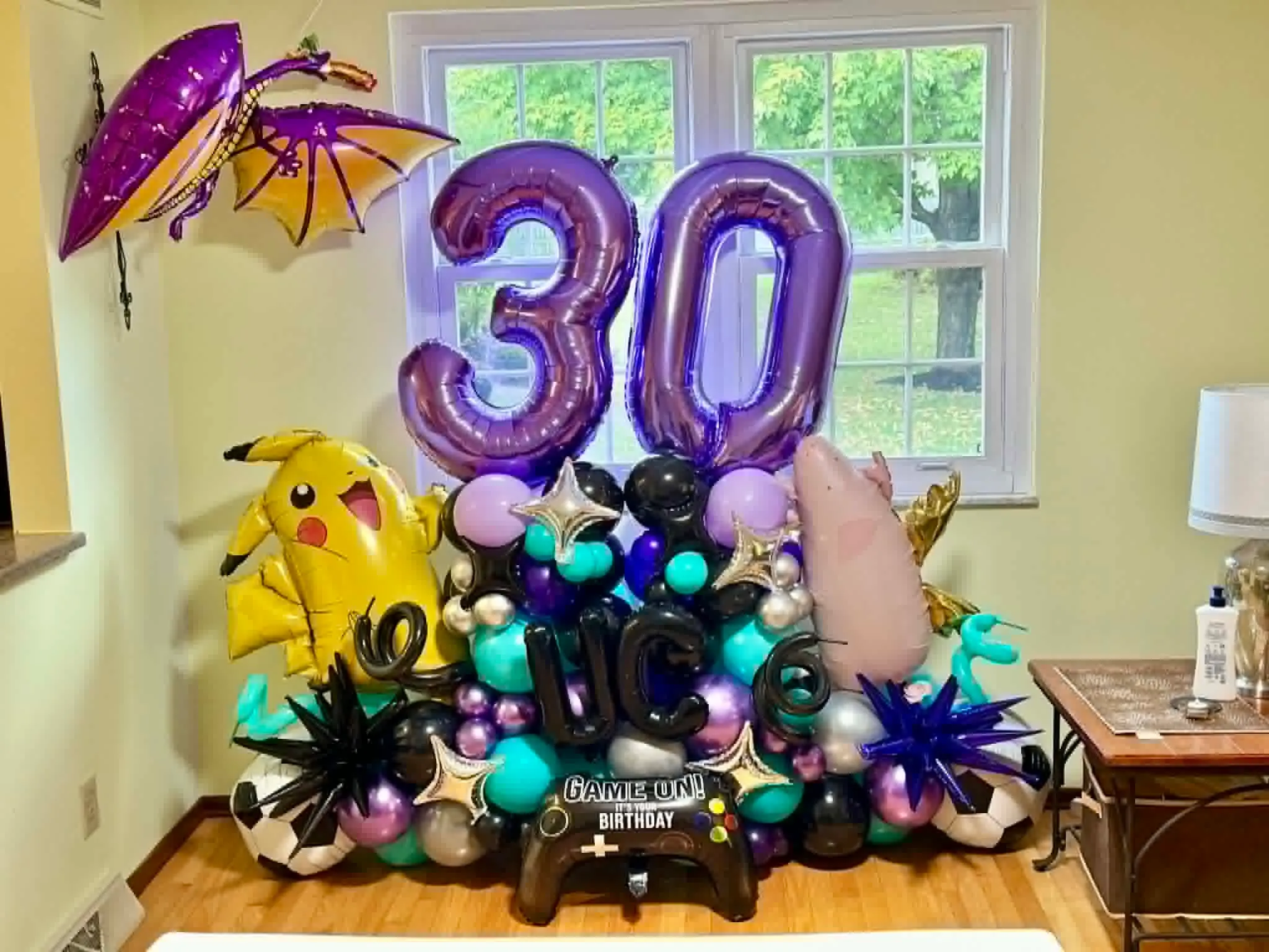 Balloon marquee with giant purple 30 numbers over teal, black, silver and lilac balloons with game controller, star and character foils