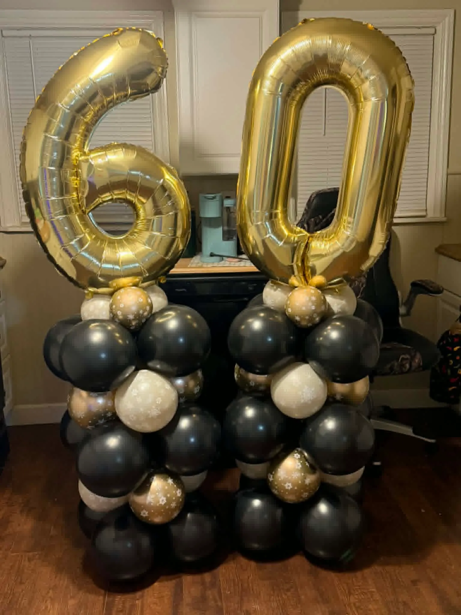 Two black, gold and pearl balloon columns topped with giant gold 6 and 0 number balloons